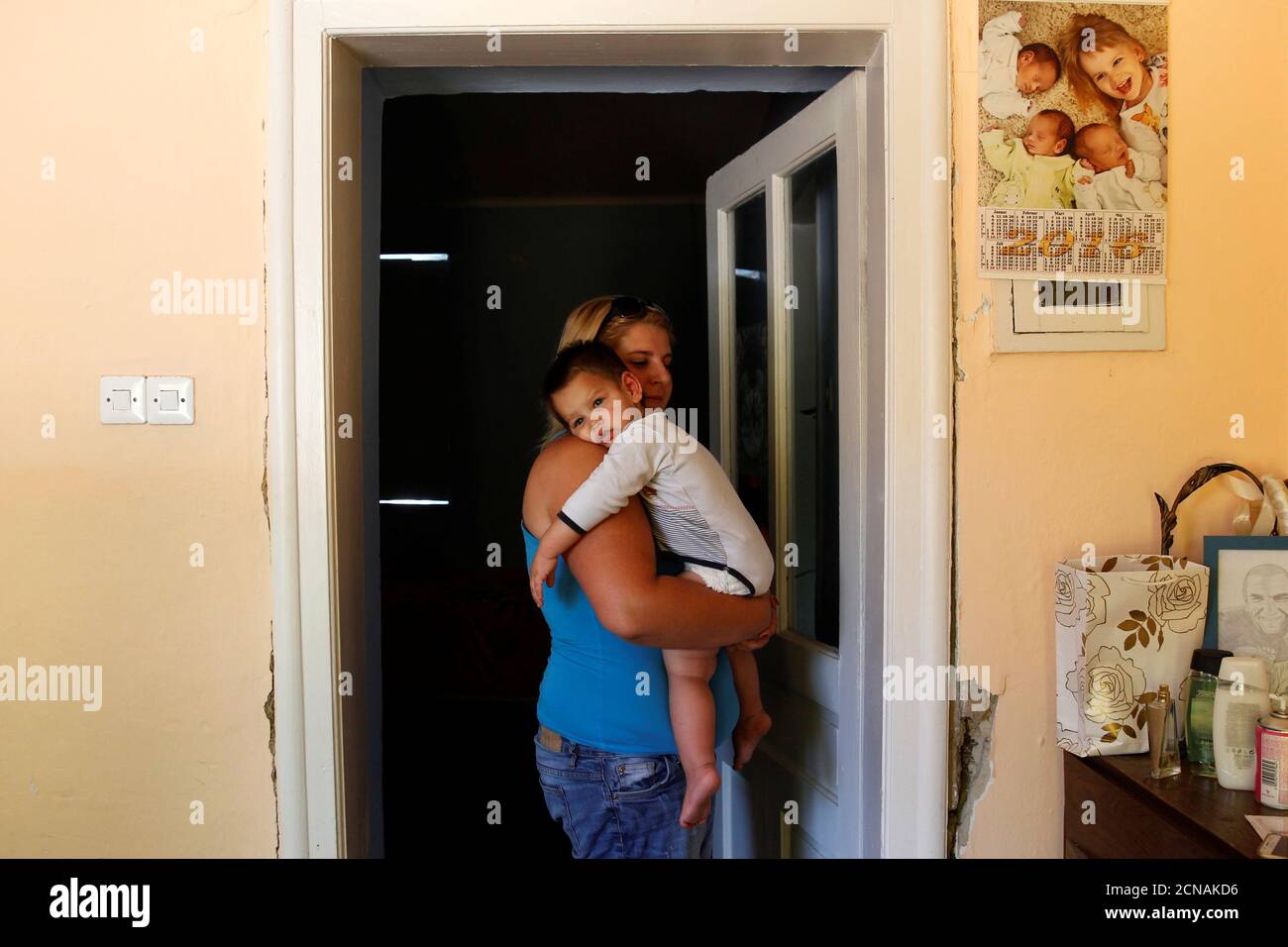Nikoletta Futo holds one of her triplet sons in the doorway to their  darkened bedroom in Kanjiza, Serbia, July 7, 2017, after a grant from the  Hungarian government enabled the family of