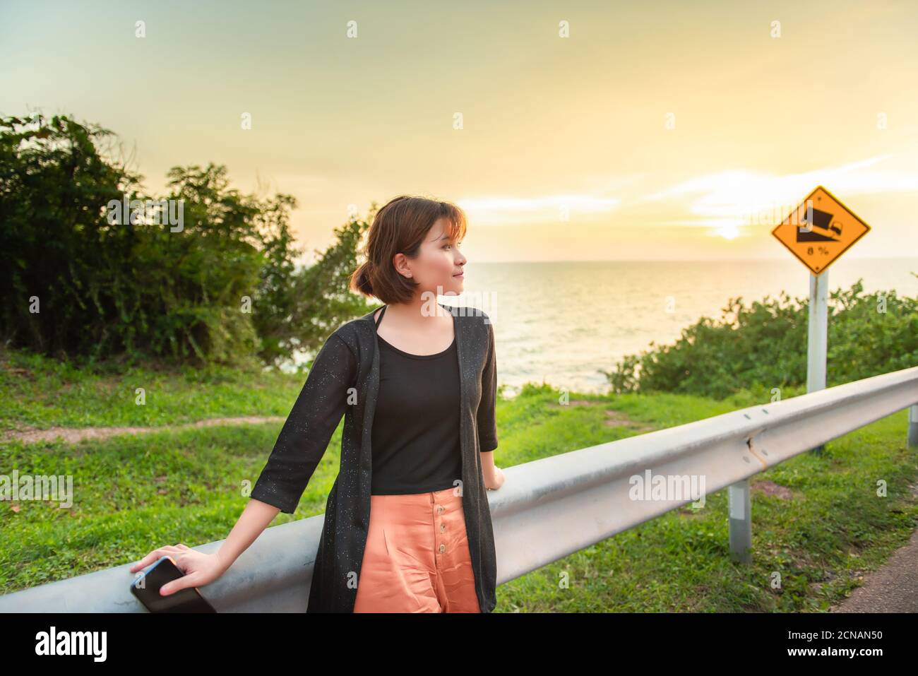 Travel and freedom,Asian women are feeling free and smiling against a background of sunset and sea coast.The adventures and directions for travel . Stock Photo