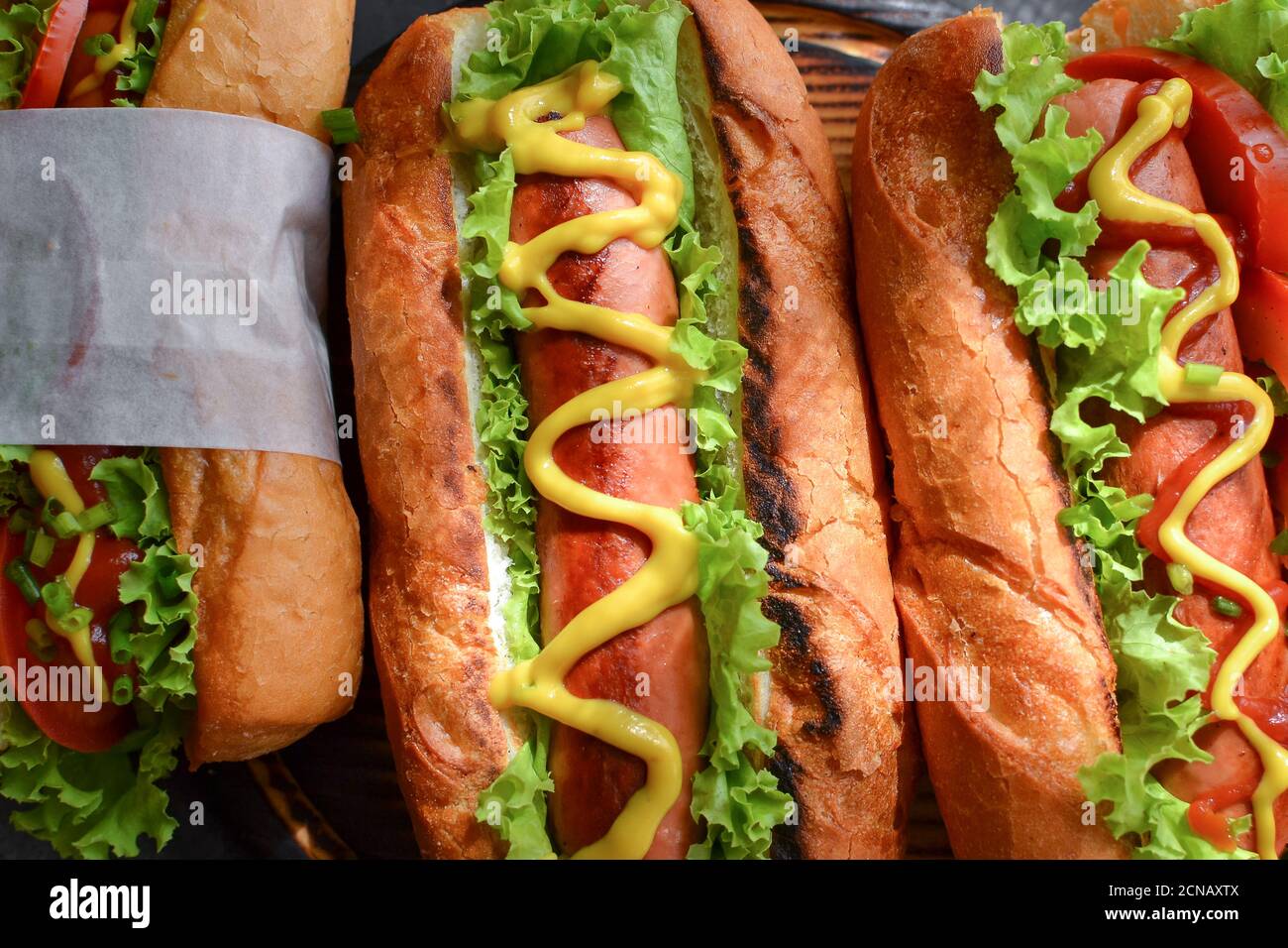 Hot dogs with various fillings. Dark background. food background with copy space. Top view. Hot dogs with mustard and ketchup, lettuce, cheese and Stock Photo