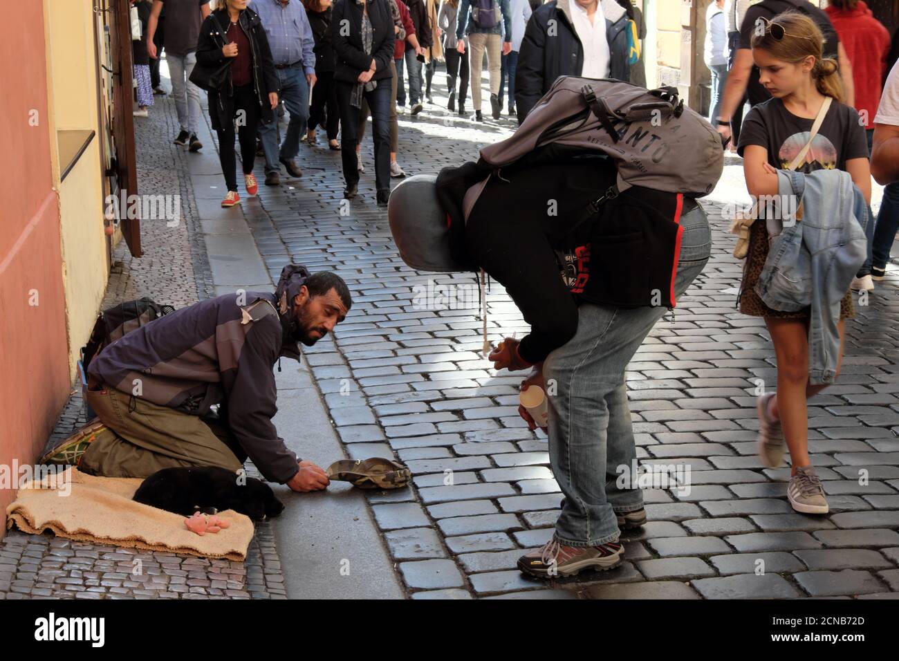 Prague, Czech Republic, October 12, 2019. A girl watches a guy chatting with a beggar. Migrant begs on the street of a European city. Stock Photo