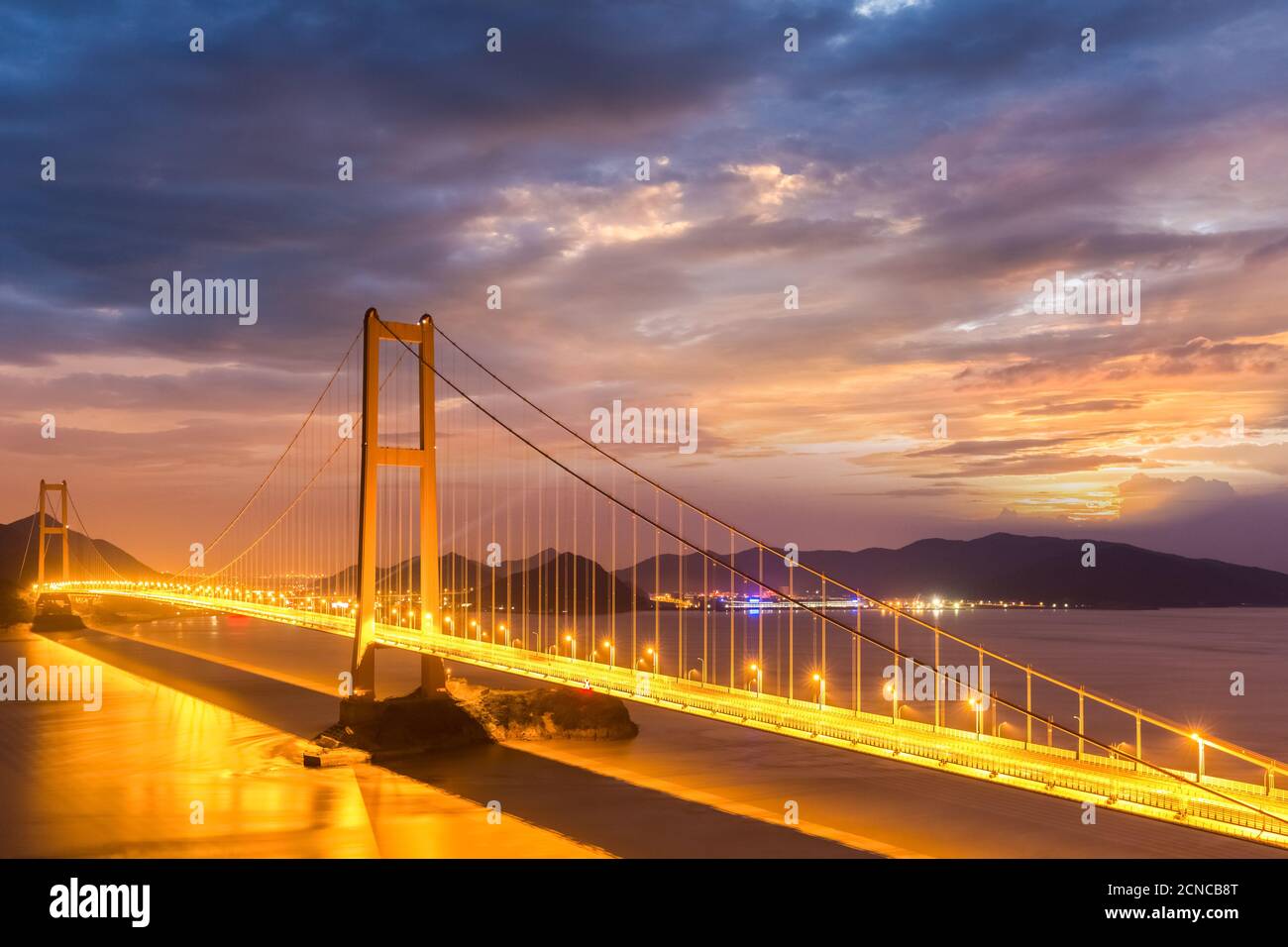 bridge spanning the sea in nightfall Stock Photo