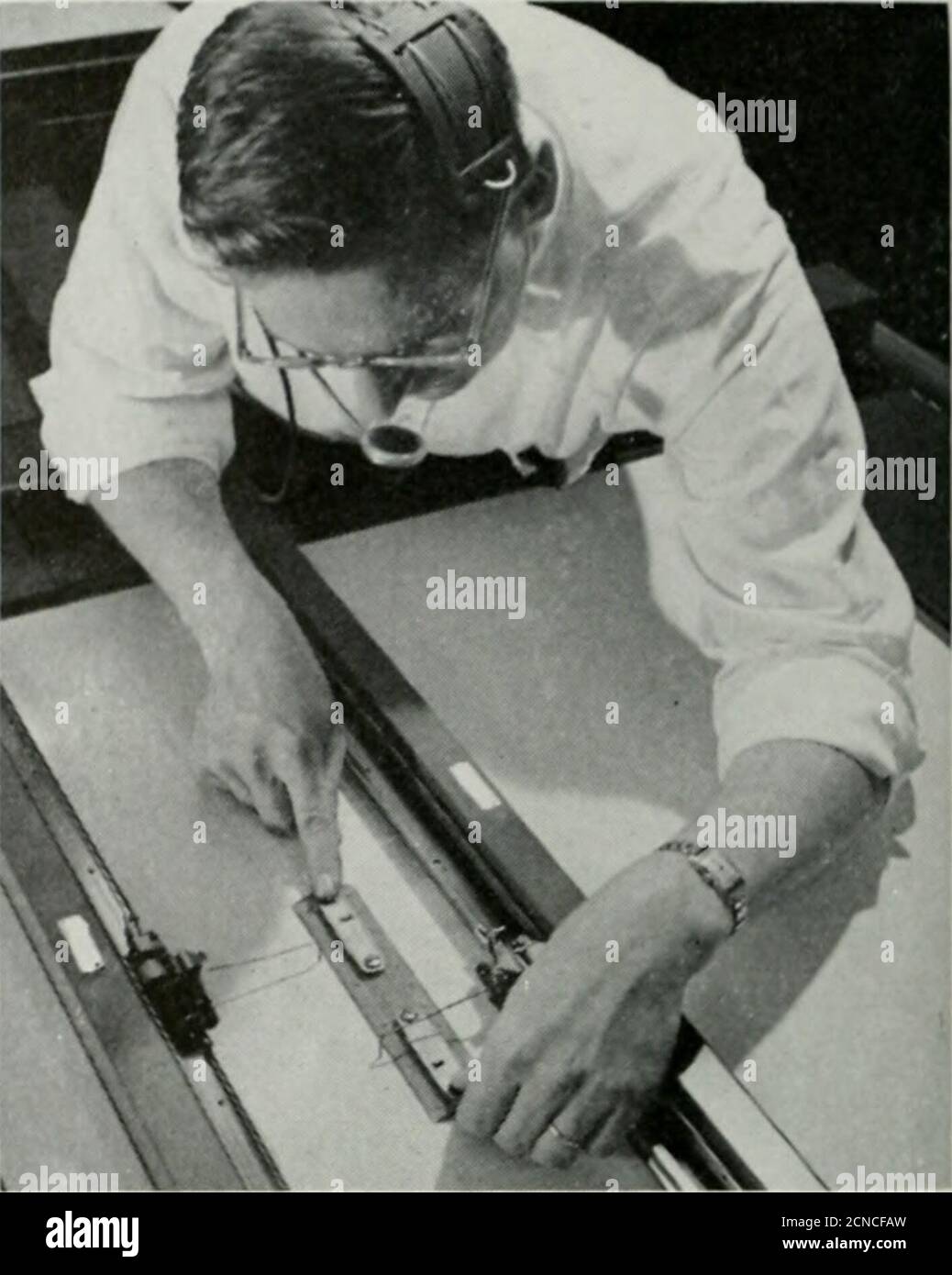 . Bell telephone magazine . Bell Laboratories engineer sets up simuhitedfiring course, during developmental stage ofNike, by plotting course of missile and target. The Simulator Master Control, special test equipment which enabled Bell Telephone Labora-tories engineers to fire many hundreds of simulated missiles without the expense of usingactual missiles on the range.. Stock Photo