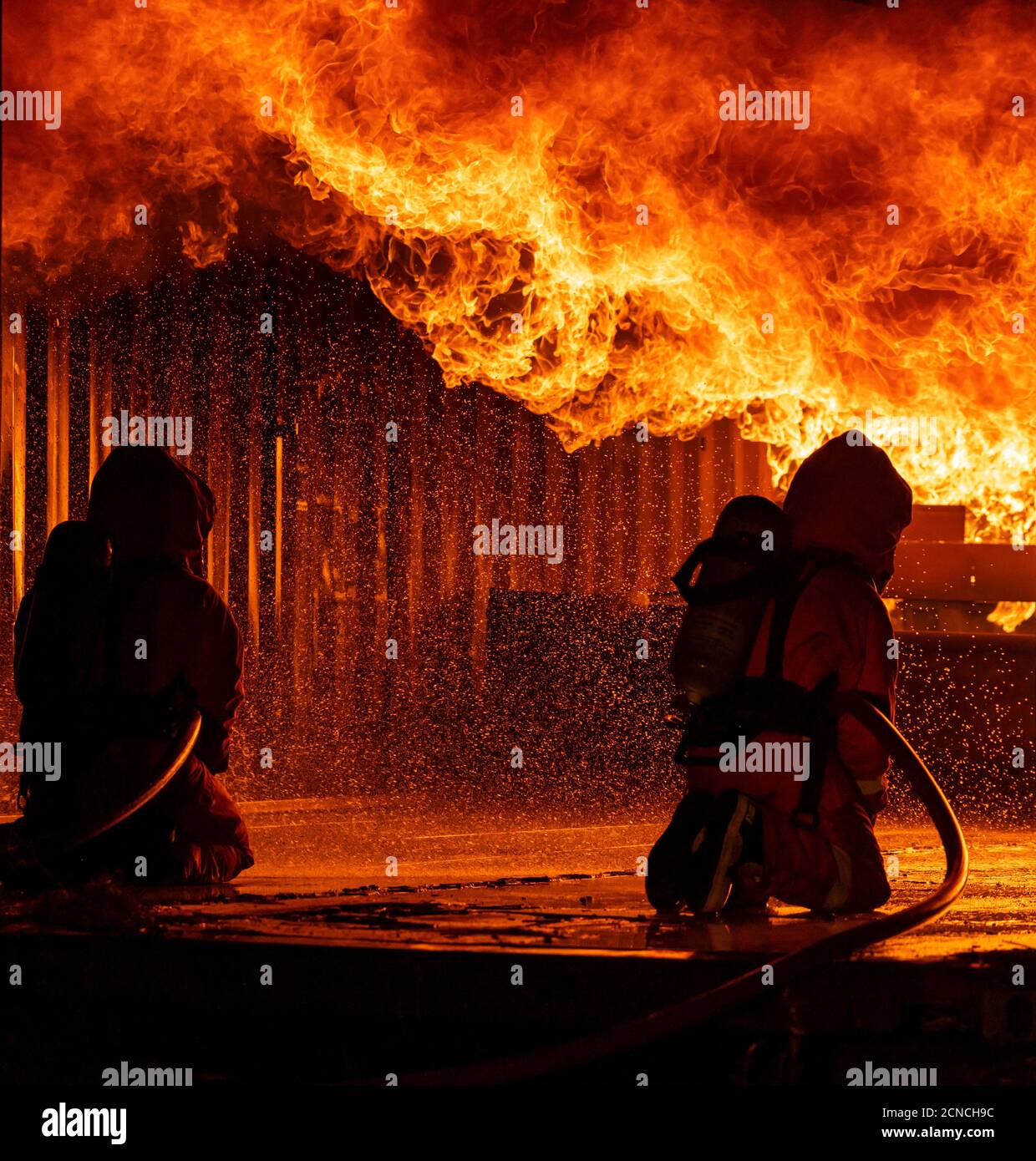 Firefighters use water fog spraying down fire flame in building. Stock Photo