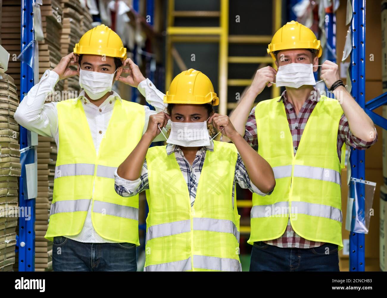 Interracial warehouse worker team putting on  face mask Stock Photo