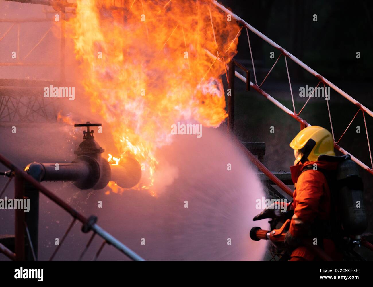 Firefighters using water fog spraying down fire from oil rig factory explosion Stock Photo