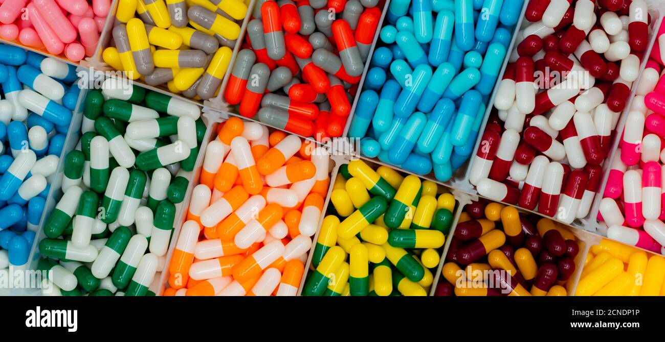 Top view of colorful capsule pills in  plastic box. Antibiotic drugs, painkiller medicine, vitamins, and supplements capsule pills. Pharmaceutical Stock Photo