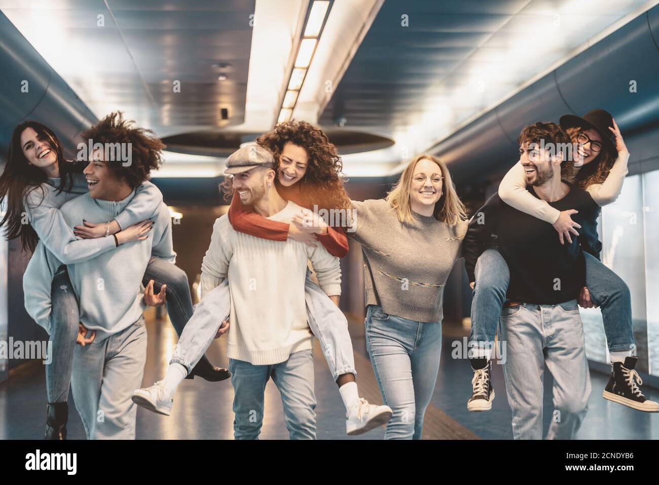 Group young friends having fun piggybacking in underground metropolitan subway - Happy trendy people enjoying nightlife and laughing together Stock Photo