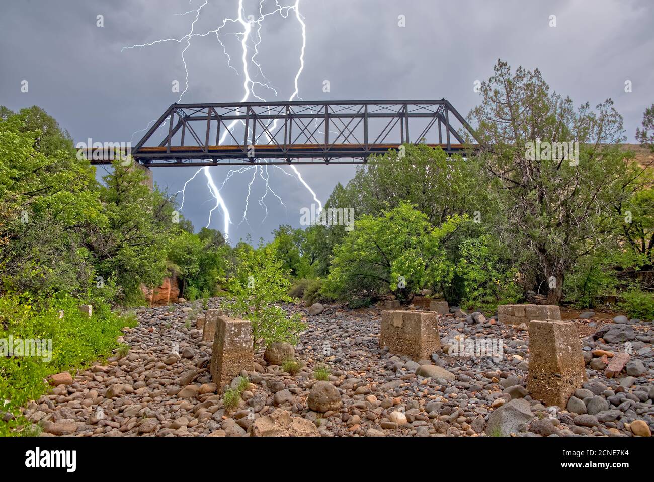 Lightning from a monsoon storm striking behind an old railroad trestle bridge that spans Bear Canyon near Perkinsville, Arizona Stock Photo