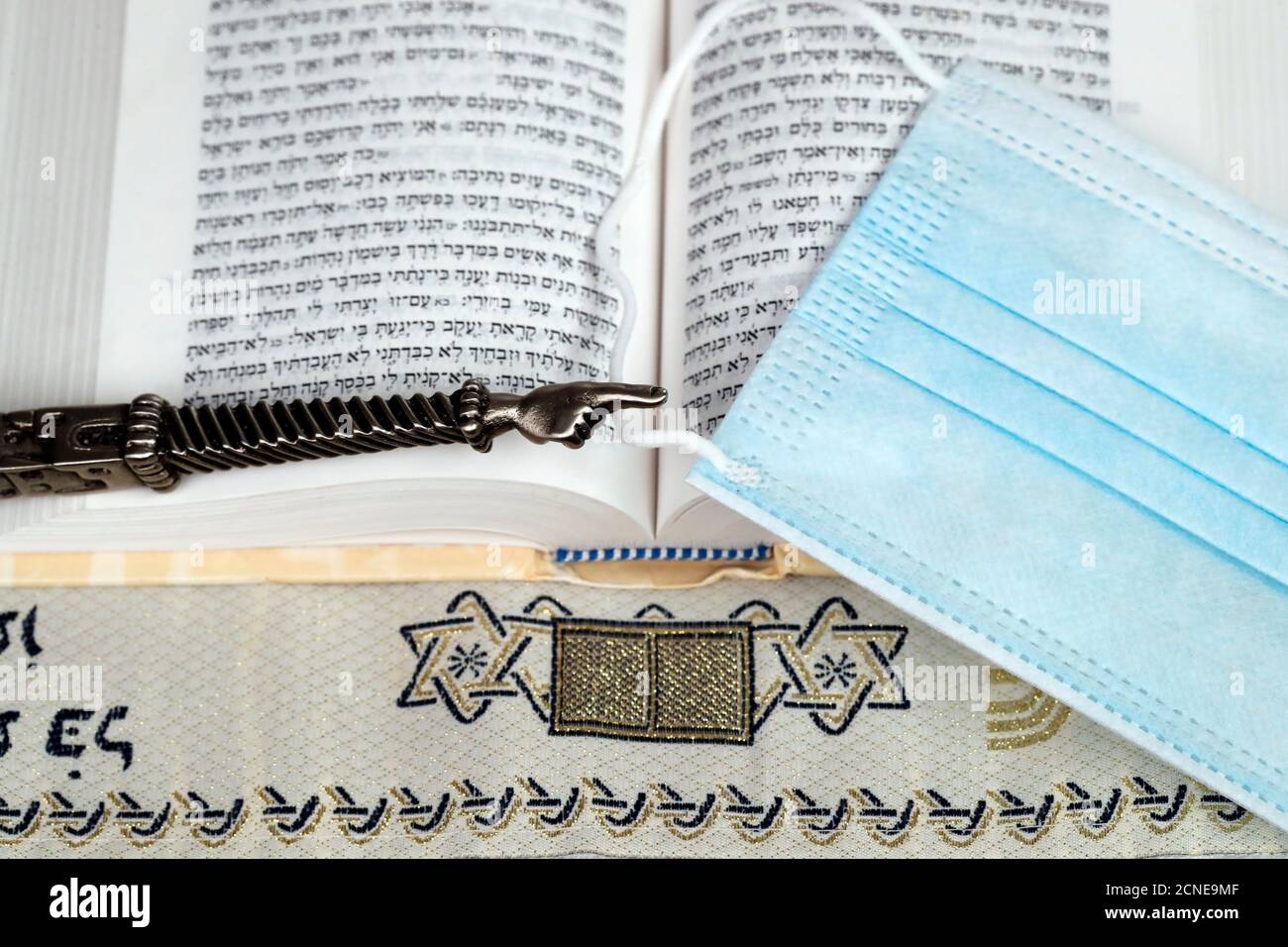 A silver Yad Jewish ritual pointer on a Torah and surgical mask, France, Europe Stock Photo