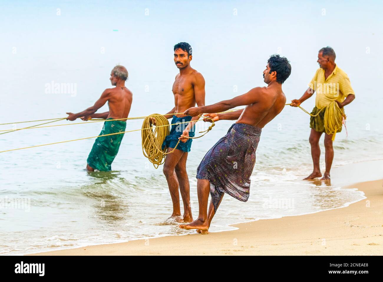 Fishermen pulling large set net to shore at busy, popular Marari Beach, Mararikulam, Alappuzha (Alleppey), Kerala, India, Asia Stock Photo
