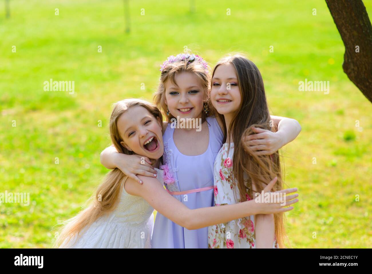 Three adorable girls in dresses hold hands in a circle holding hands ...