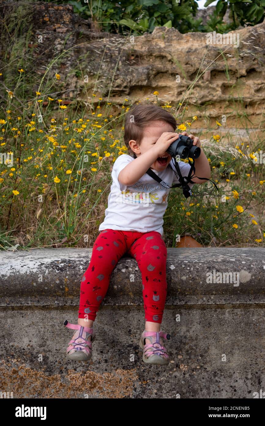 Surprised young girl looking through binoculars. Stock Photo
