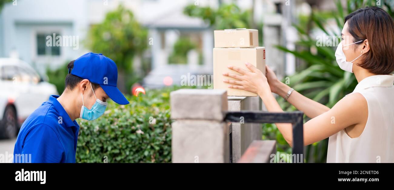 Asian customer woman take package from contactless delivery, panoramic side view. Stock Photo