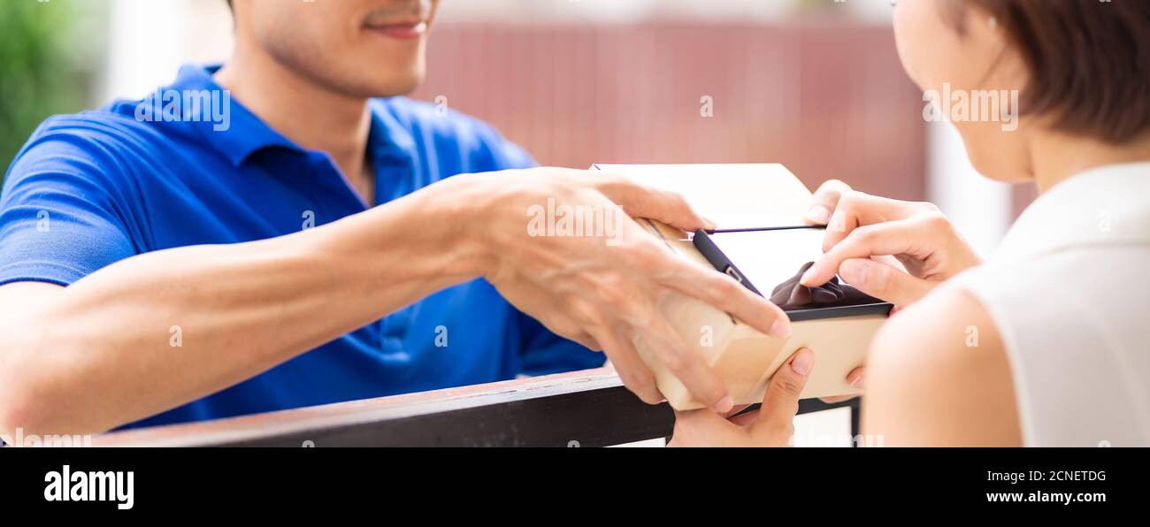 Panoramic asian customer woman sign for recieve package delivery. Stock Photo