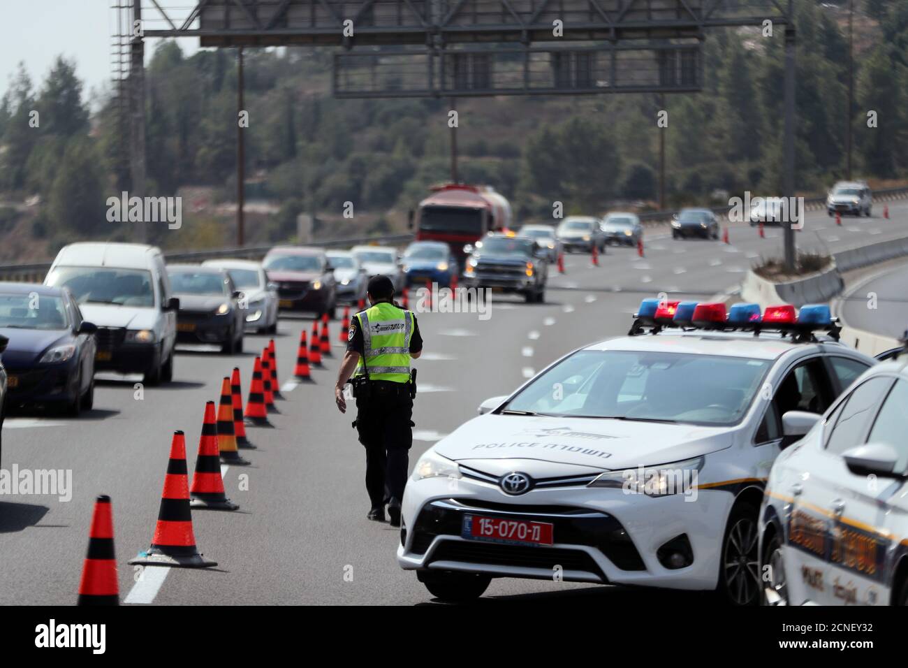 A policeman sets trafic control poles before Israel will enter a second nationwide lockdown amid a resurgence in new coronavirus disease (COVID-19) cases, forcing residents to stay mostly at home during the Jewish high-holiday season, on the main road leading to Jerusalem in Ein Hemd September 18, 2020. REUTERS/Ronen Zvulun Stock Photo