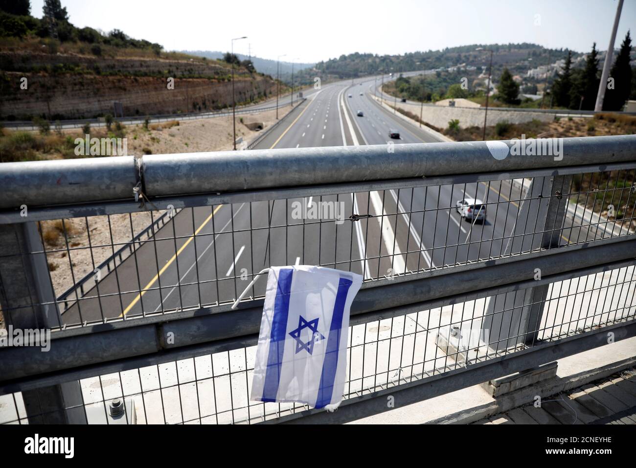 An Israeli national flag is seen on a bridge before Israel will enter a second nationwide lockdown amid a resurgence in new coronavirus disease (COVID-19) cases, forcing residents to stay mostly at home during the Jewish high-holiday season, on the main road leading to Jerusalem in Ein Hemd September 18, 2020. REUTERS/Ronen Zvulun Stock Photo