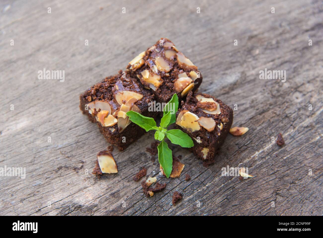 Piece of stack homemade dark chocolate brownies topping with almonds slices and mint on wood table. Stock Photo