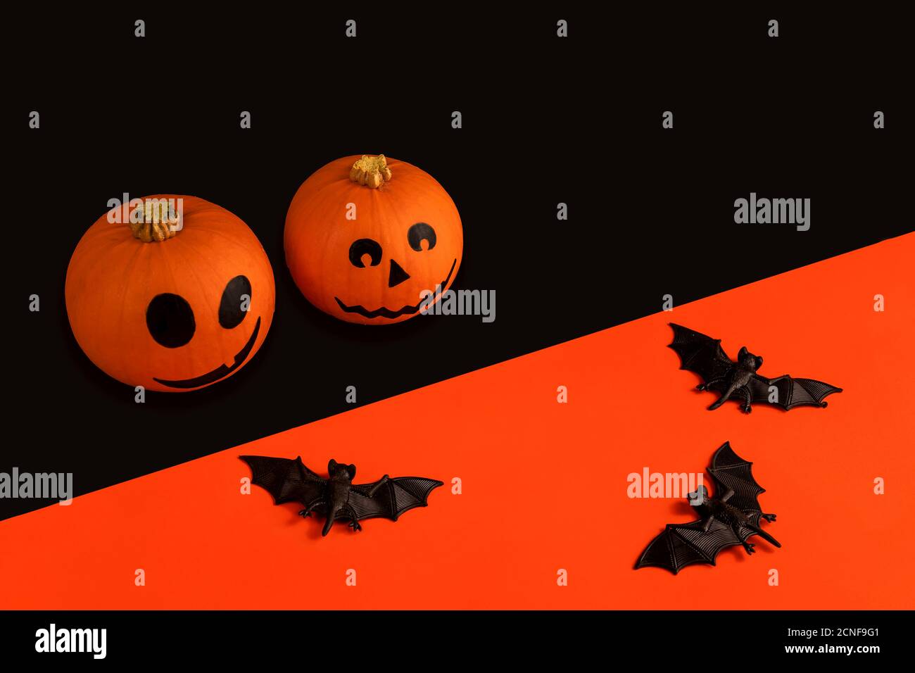 Little pumpkins with painted faces for Halloween and bats on orange and ...