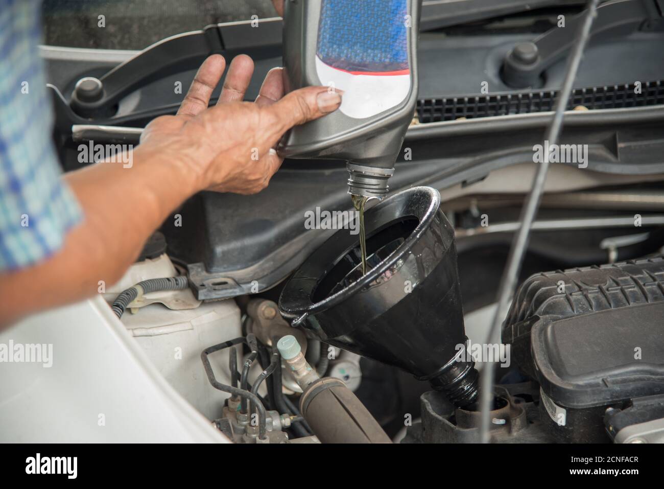Mechanic draining engine oil from a car for an oil change Stock Photo