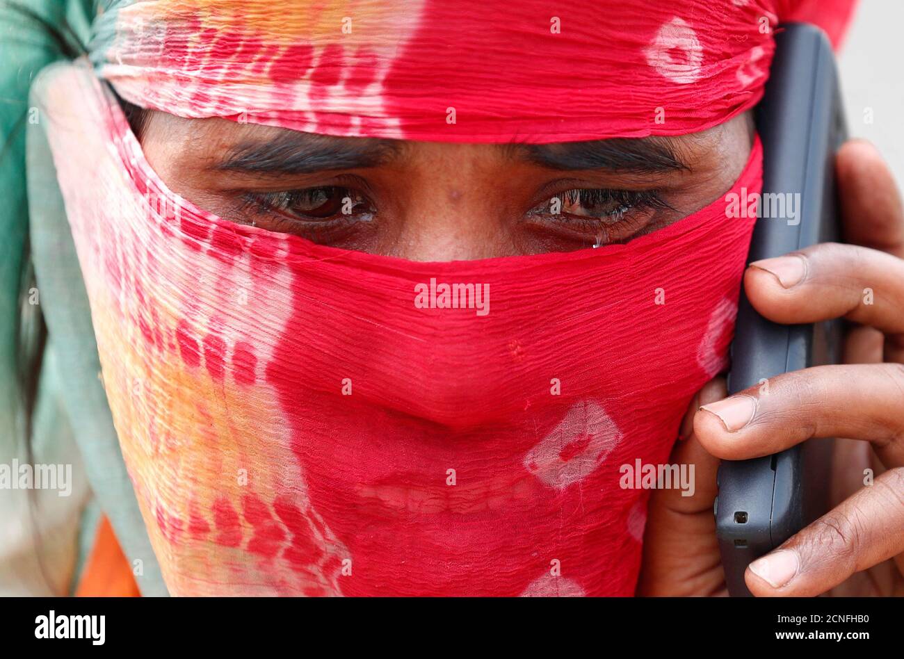The wife of a migrant worker cries as she talks to a relative on a mobile phone after police stopped them at a checkpoint while they were walking on a highway to return to their home state in the northern state of Uttar Pradesh, during an extended nationwide lockdown to slow the spread of the coronavirus disease (COVID-19), in Ghaziabad, in the outskirts of New Delhi, India, May 13, 2020. REUTERS/Adnan Abidi Stock Photo