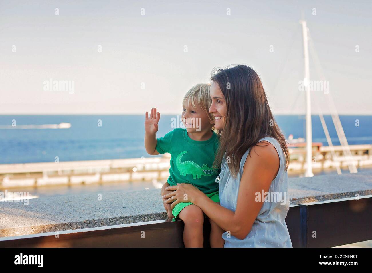 Mother and toddler child, blond boy, standing near the sea ...