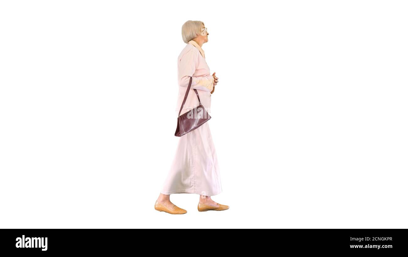 Attractive intelligent senior woman walking on white background. Stock Photo
