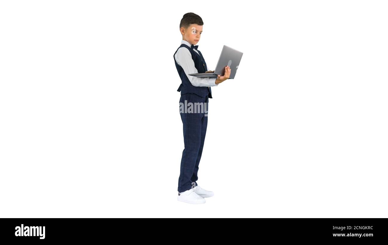Concentrated boy in a bow tie and waistcoat using laptop compute Stock Photo