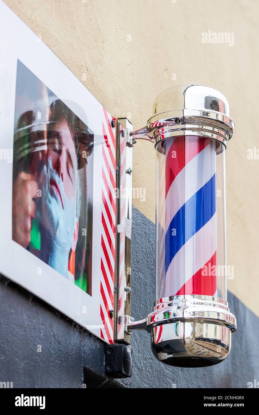 Traditional red, white and blue barber's sign pole outside a gents hairdresser's shop, Kilwinning, Scotland, UK Stock Photo