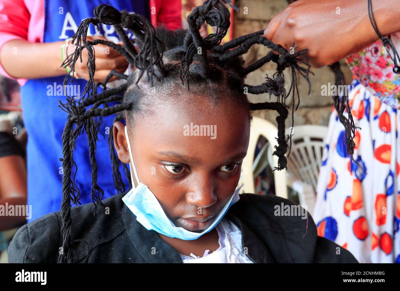Martha Apisa, 12, gets plaited with the 'coronavirus' hairstyle, designed to emulate the prickly appearance of the virus under a microscope, as a fashion statement against the spread of the coronavirus disease (COVID-19), at Mama Brayo Beauty Salon within Kambi-Muru village of Kibera slums in Nairobi, Kenya April 29, 2020. Picture taken April 29, 2020. REUTERS/Thomas Mukoya Stock Photo