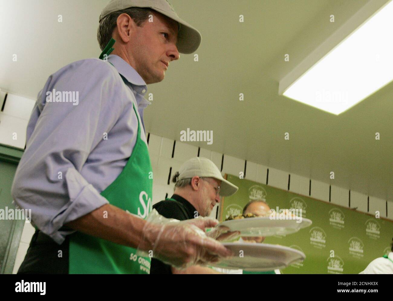 U.S. Treasury Secretary Timothy Geithner carries plates of food as he serves lunch to the homeless and other clients at the 'So Others May Eat'  (SOME) soup kitchen and social service center for the poor in downtown Washington, June 25, 2009.    REUTERS/Jim Bourg  (UNITED STATES POLITICS) Stock Photo