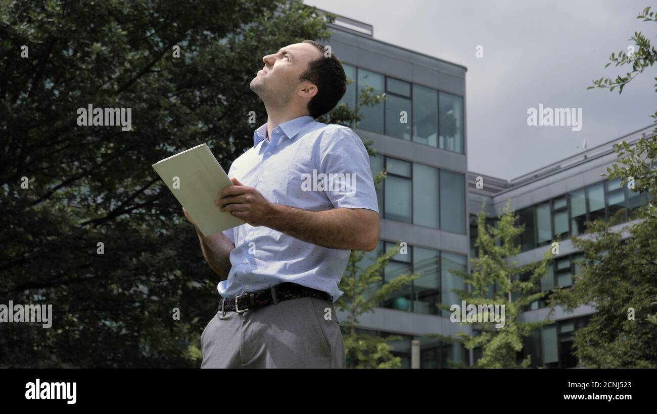 Businessman standing in city park, near office buildings using t Stock Photo