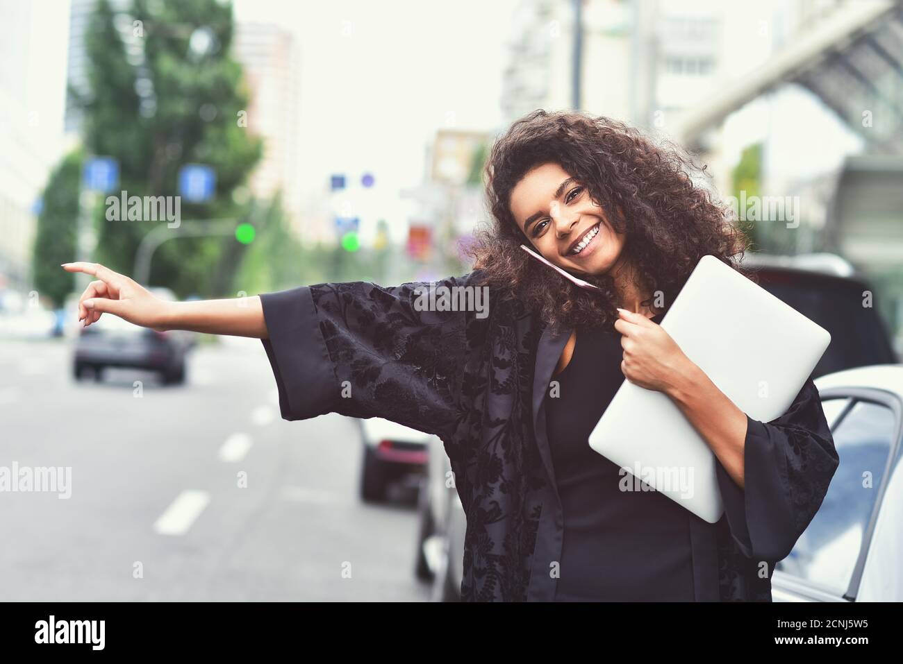 Positive emotions. Happy mixed race woman use a phone, try take a taxi. Stock Photo