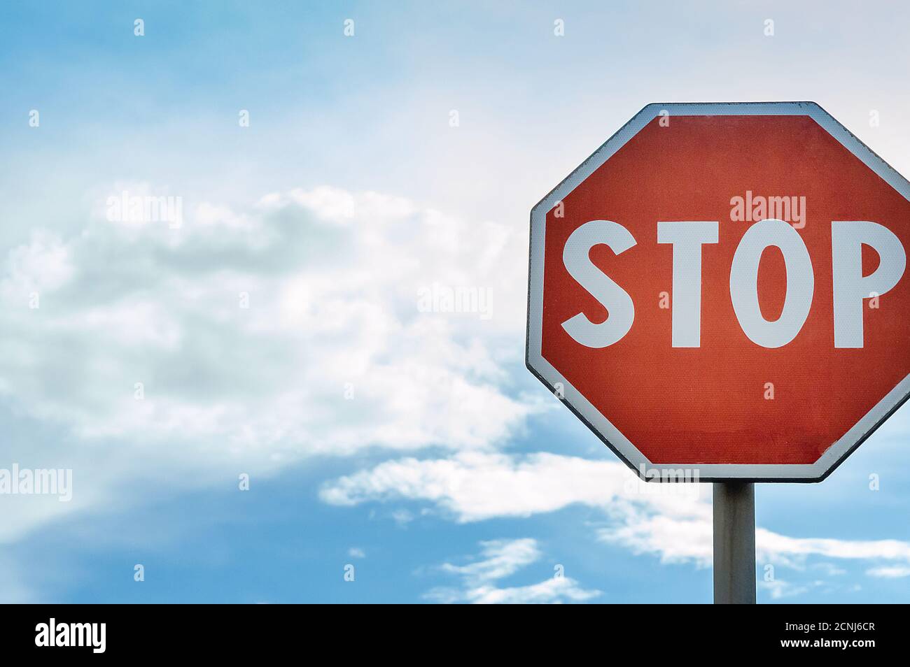 Red Stop Sign with Blue Sky and Clouds Background Stock Photo