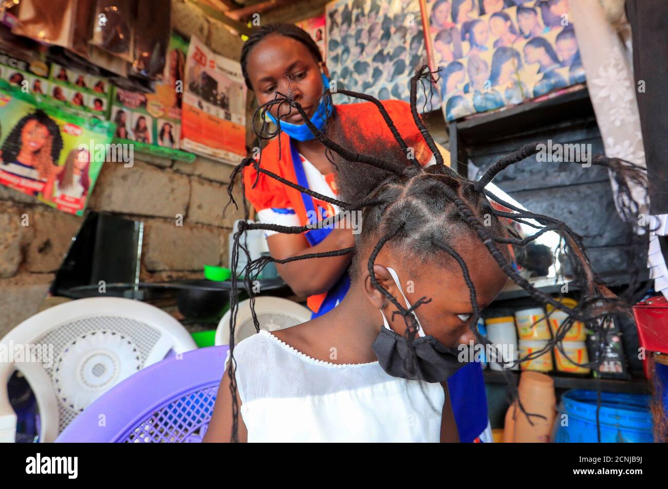 Stacy Ayuma, 8, gets plaited with the 'coronavirus' hairstyle, designed to emulate the prickly appearance of the virus under a microscope, as a fashion statement against the spread of the coronavirus disease (COVID-19), at Mama Brayo Beauty Salon within Kambi-Muru village of Kibera slums in Nairobi, Kenya April 29, 2020. Picture taken April 29, 2020. REUTERS/Thomas Mukoya Stock Photo
