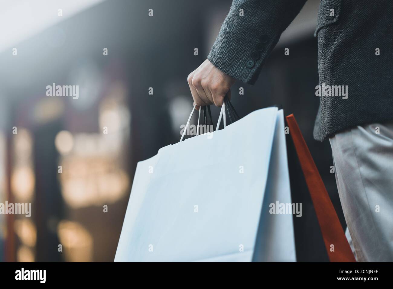 Concept of man shopping and holding bags, closeup images. Close up of paper shopping bags in male hand. Stock Photo