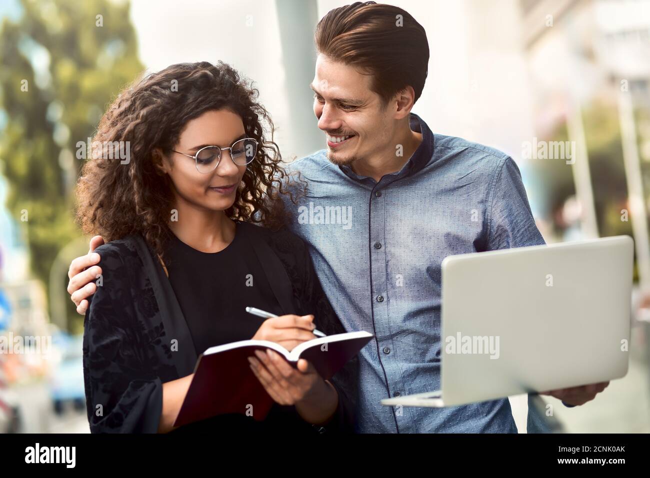 Business meeting. Man and woman discussing work and looking at the laptop screen. Working together in the open air. Stock Photo