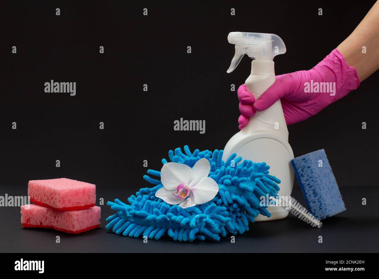 Female hand in a rubber glove holding a plastic bottle of washing ...