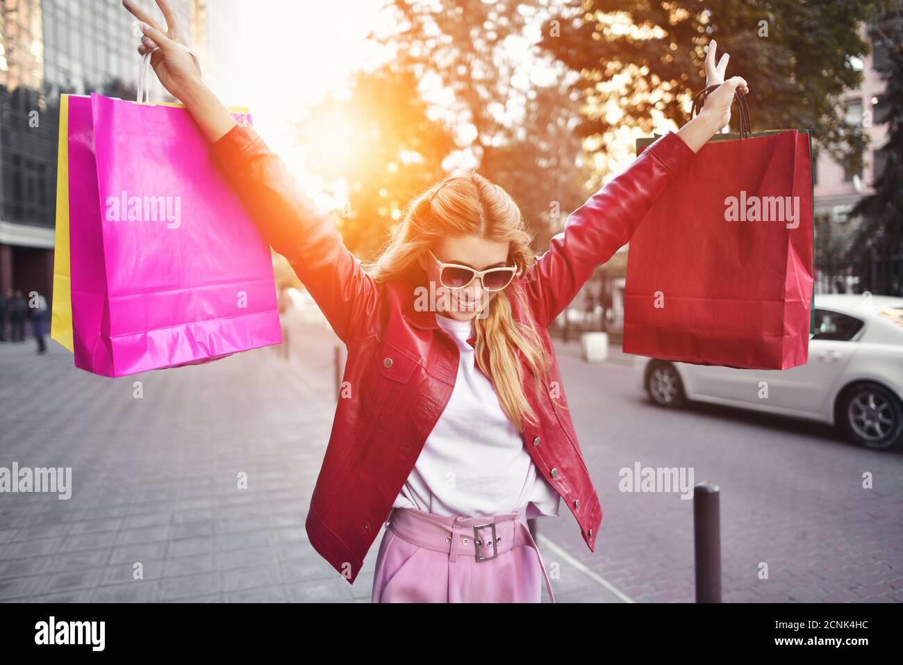 Beautiful smiling girl in sunglasses is holding shopping bags and ...