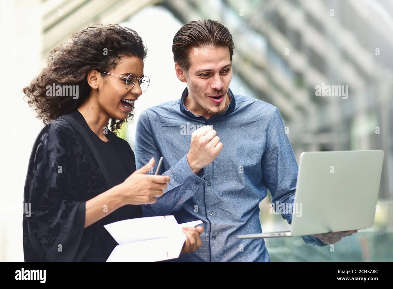 Business meeting. Man and woman discussing work and looking at the laptop screen. Working together in the open air. Stock Photo