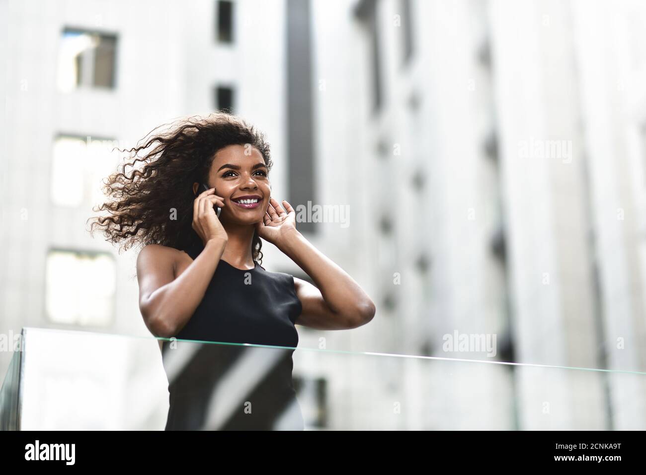 Pretty mixed race businesswoman speak by phone in city. Stock Photo