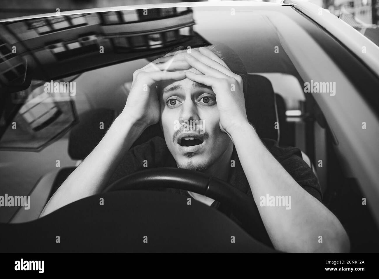 Young man driving a car shocked about to have traffic accident, windshield view. Stock Photo