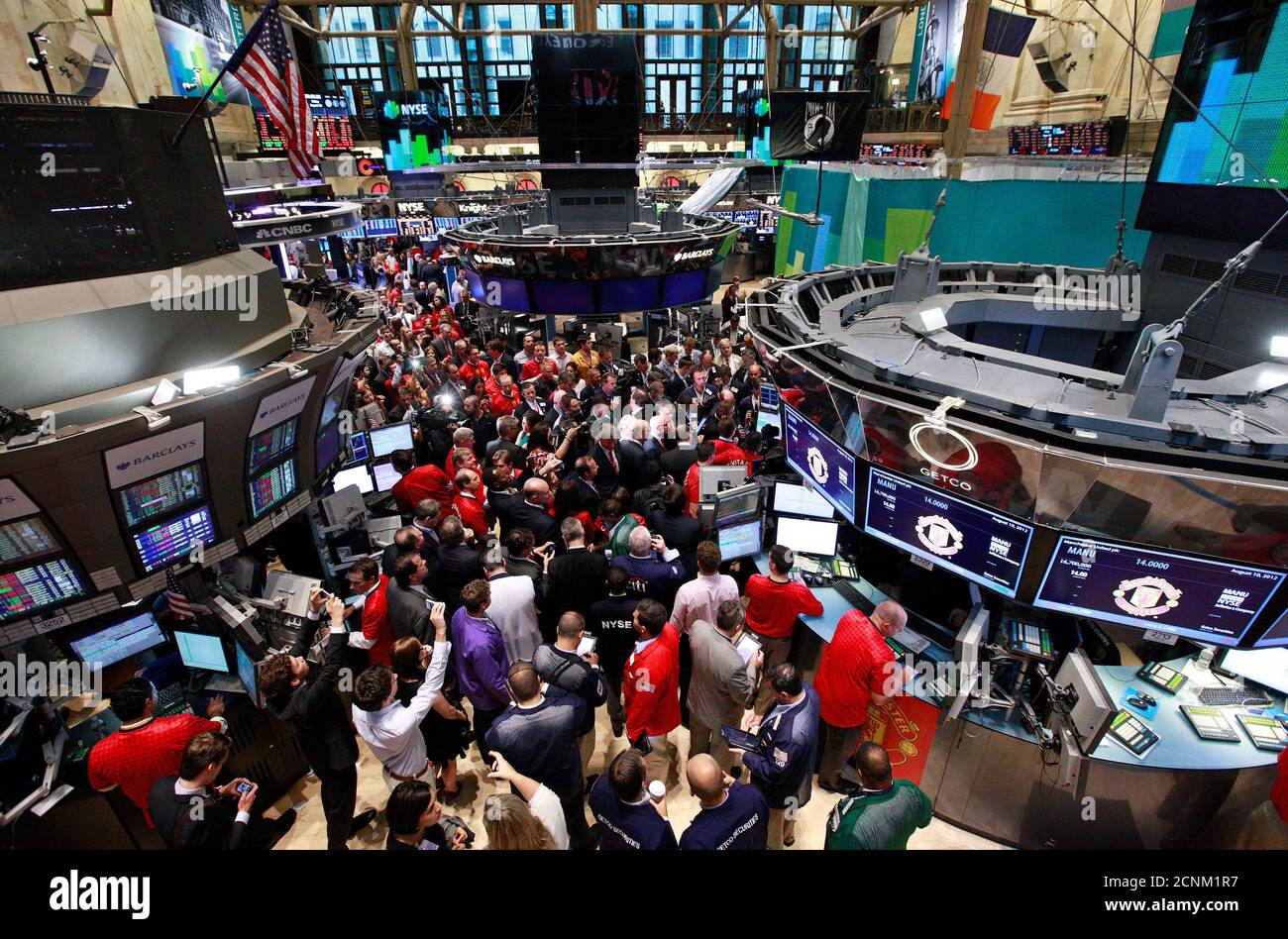 People gather at the post for the start of trading of Manchester United Ltd following its initial public offering on the floor of the New York Stock Exchange, August 10, 2012. Shares in Manchester United priced below expectations and were essentially flat in early trading on Friday, a disappointing stock market debut for the world's most famous soccer club and most valuable sporting team. REUTERS/Brendan McDermid (UNITED STATES - Tags: BUSINESS SPORT SOCCER) Stock Photo