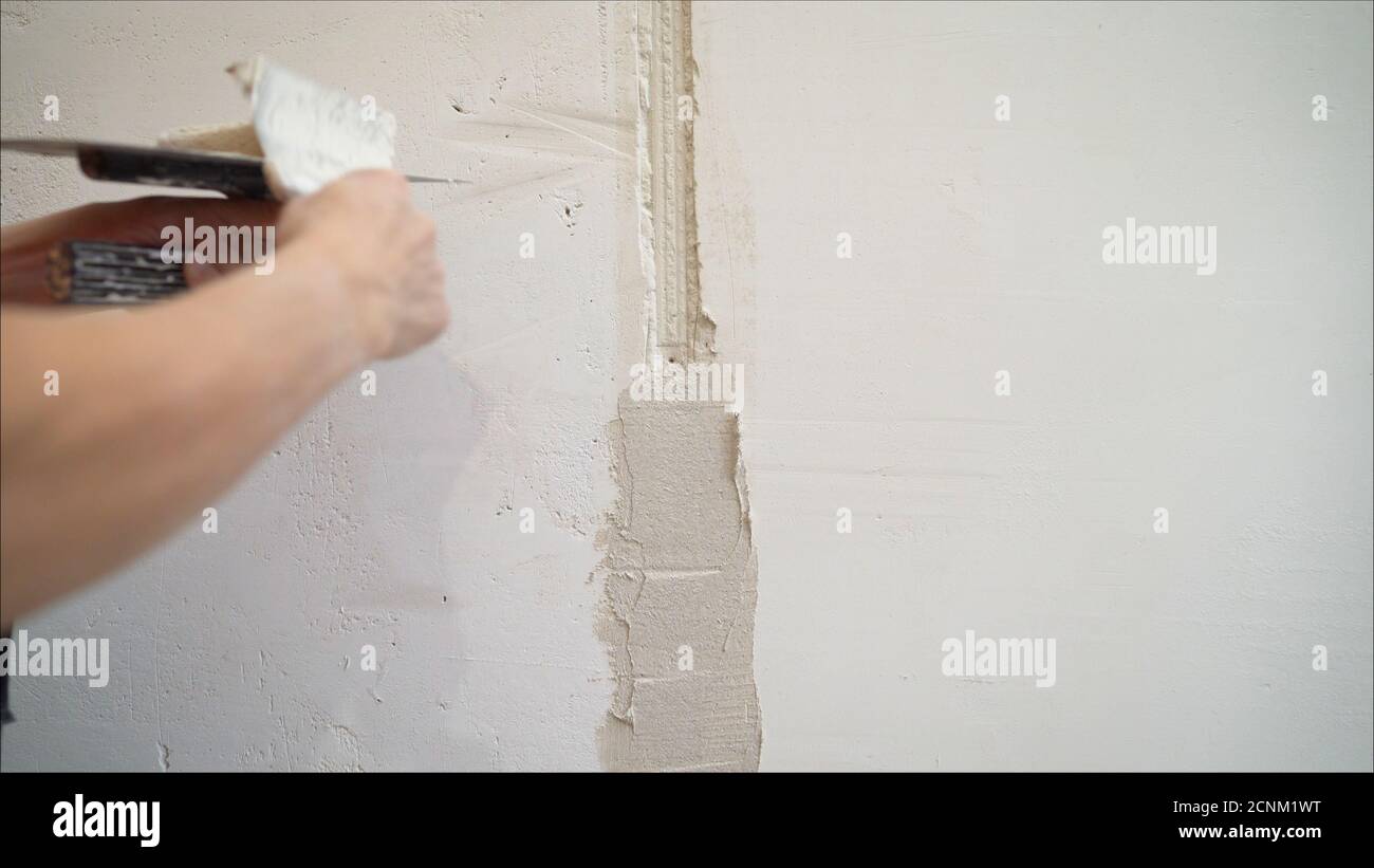 Decorative plaster coating. Man does ragged texture on the wall using a spatula. plaster application on the wall Stock Photo