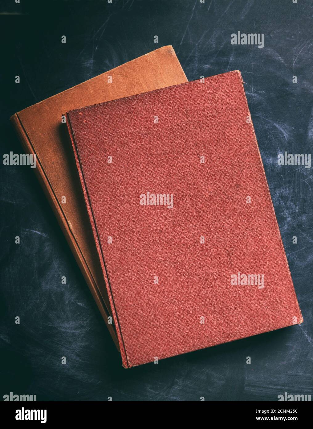 Blank books on black board background. Old vintage cloth hard cover book, cover template, top view, vertical Stock Photo