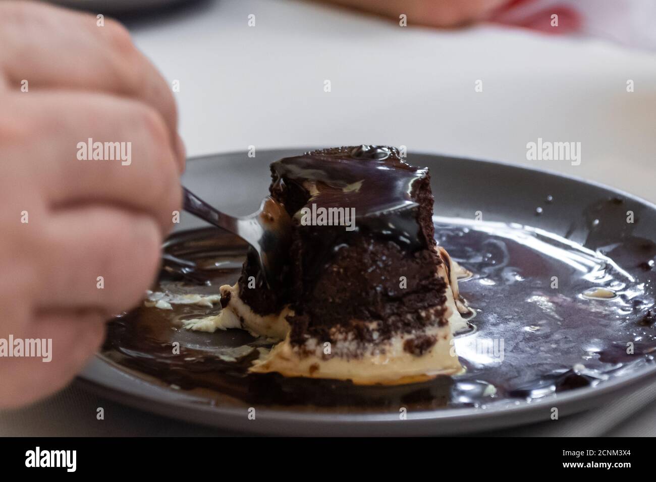 close-up of a person's hand with a spoon about to eat a piece of cake Stock Photo