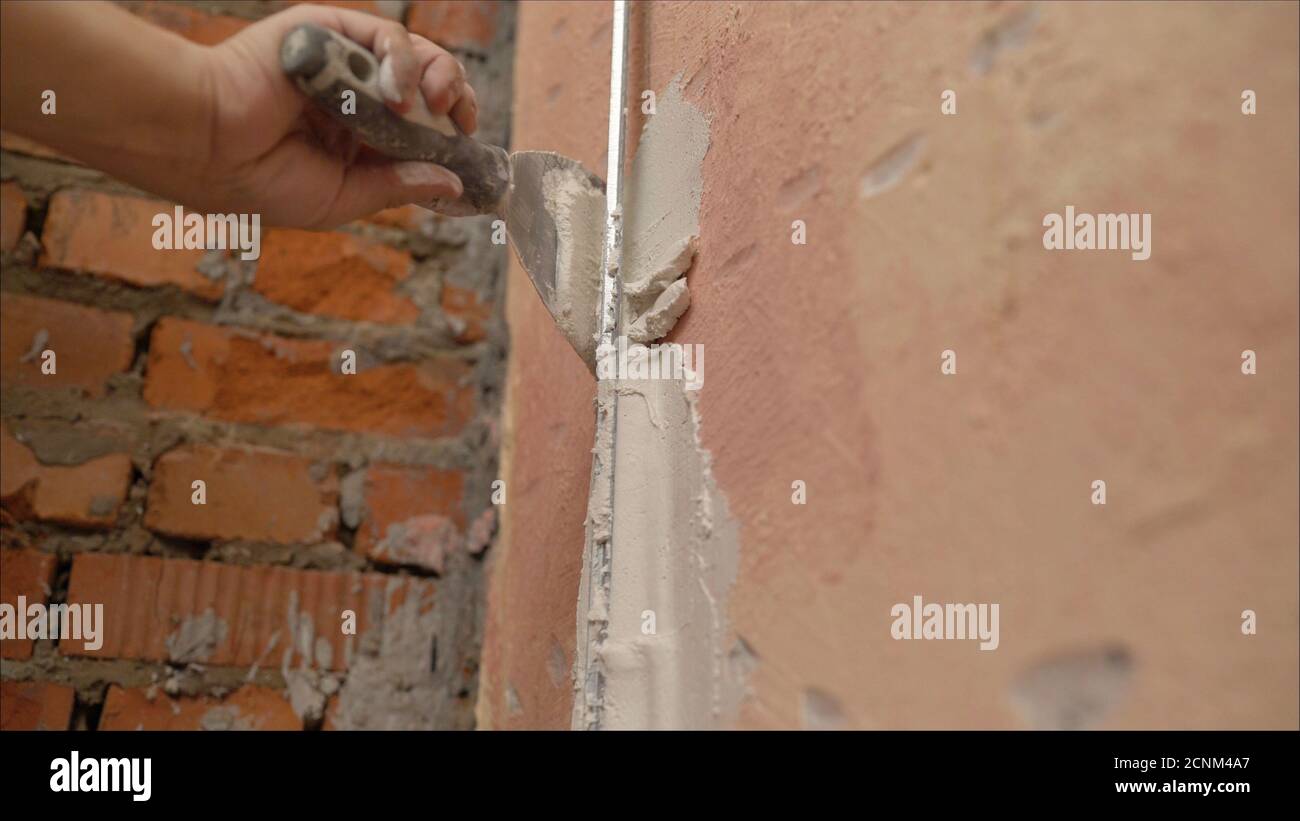 Decorative plaster coating. Man does ragged texture on the wall using a spatula. plaster application on the wall Stock Photo