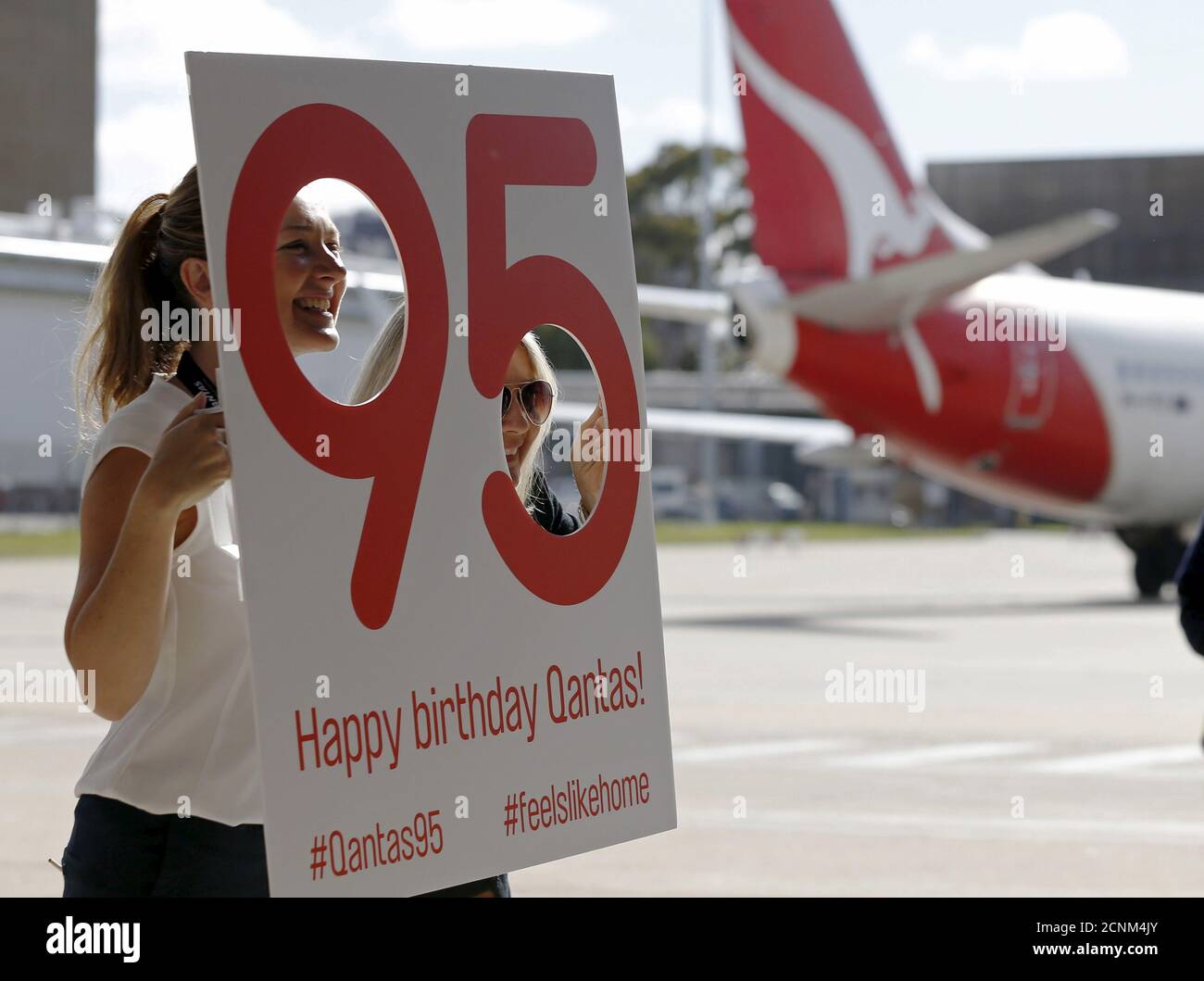 Qantas staff pose for a picture alongside a Qantas aircraft at Sydney International Airport, November 16, 2015.  Qantas on Monday marked its 95th anniversary with the unveiling of the Retro Roo II, finished in colours resembling the company's 1959 livery. REUTERS/Jason Reed Stock Photo