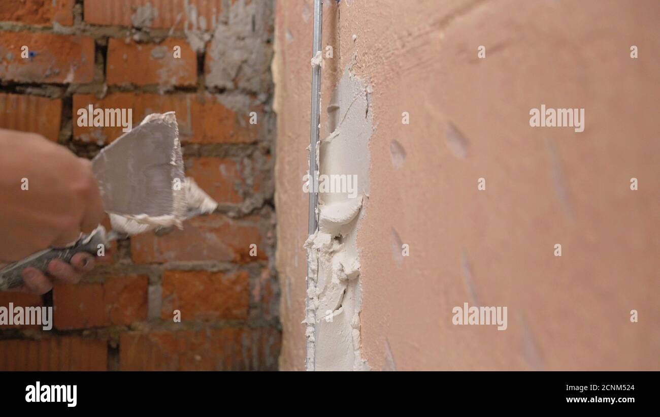 Decorative plaster coating. Man does ragged texture on the wall using a ...