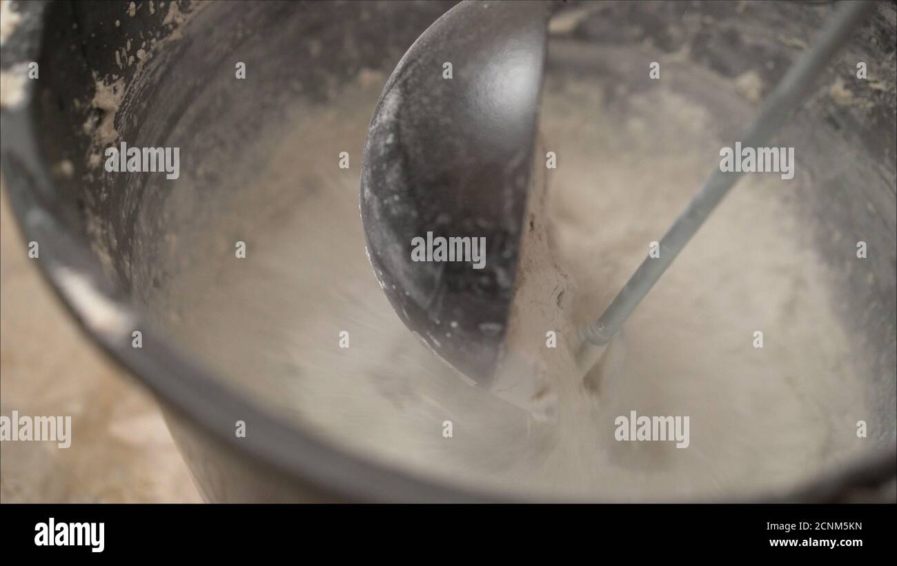 Pouring water from a bucket into the centre of dry cement mix Stock Photo -  Alamy