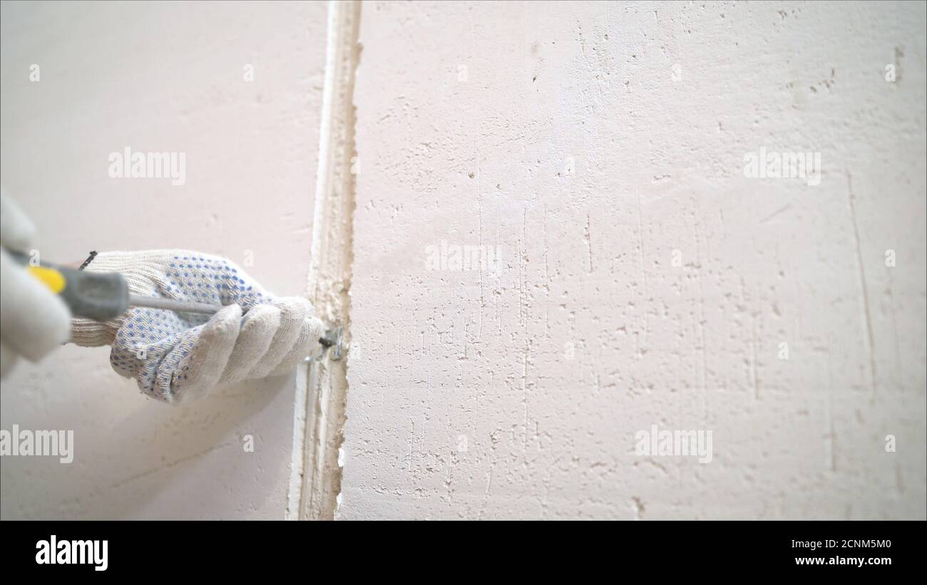 A professional disinfector in overalls processes the walls from mold with a brush. Removal of black fungus in the apartment and house. Aspergillus Stock Photo